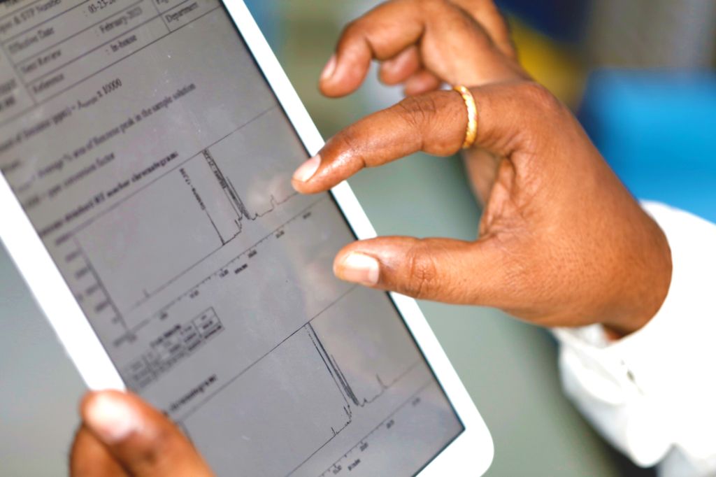 Close-up of a researcher analyzing scientific data on a tablet, showcasing a detailed chromatogram graph. The image highlights the use of digital tools for productivity, precision, and data-driven decision-making in scientific research at Sai Life Sciences.