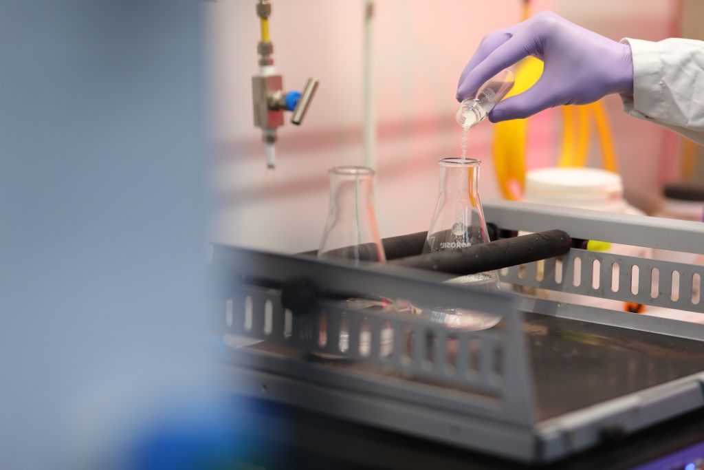 Scientist at Sai Life Sciences' Integrated Campus in Hyderabad conducting a precision chemical experiment, highlighting advanced research and development capabilities.